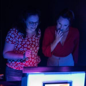 Photographie de trois personnes en train de jouer chez Musi'Quiz. Elles se tiennent debout derrière un pupitre de jeu.